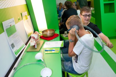 Junge hält sich einen Schlauch mit einem Trichter ans Ohr